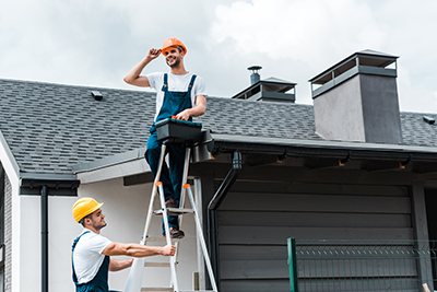 Barnegat chimney service employees; 1 on the top of a ladder on the roof, 1 holding the ladder